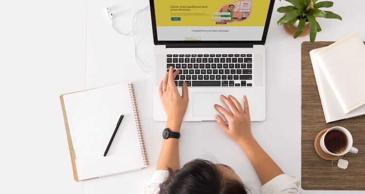 a person sitting at a desk with a laptop and a coffee cup