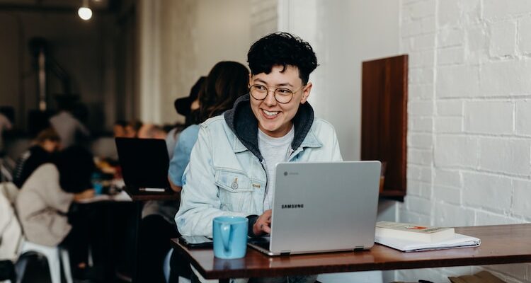 smiling man sitting and using Samsung laptop near people