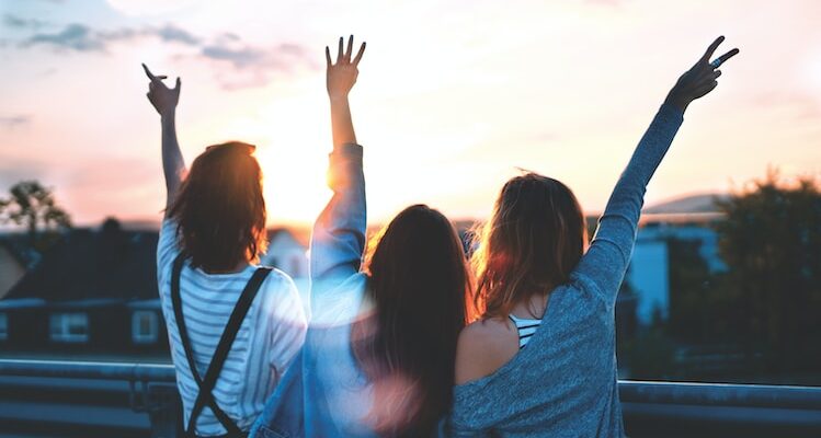 photo of three women lifting there hands 