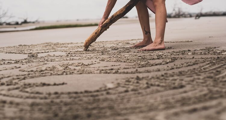 a woman digging in the sand with a stick