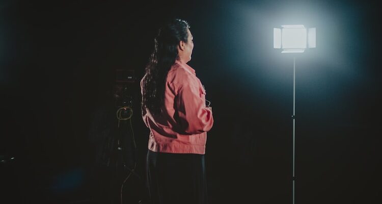 a woman standing in front of a light in the dark